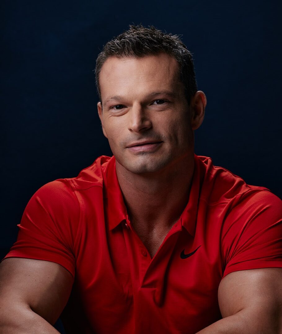 A man in red shirt sitting down with his arms crossed.